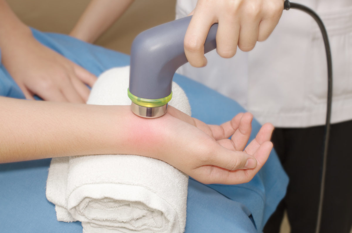 Physical therapist using ultrasound probe on woman patient 's hand for release pain